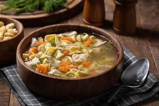 A bowl of soup with chicken and vegetables.