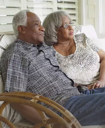 An older couple sitting on a couch together.