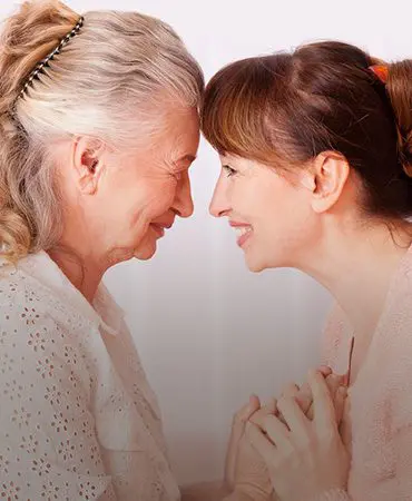 Two women are smiling and touching heads together.