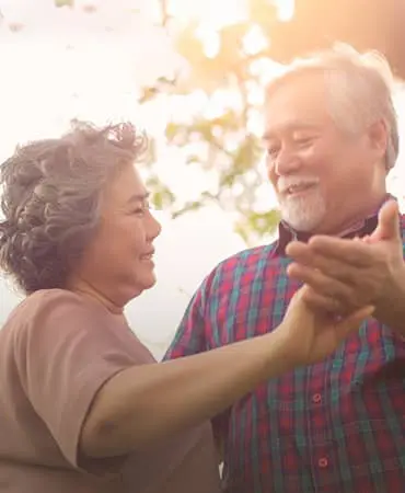 A man and woman dancing in the sunlight.